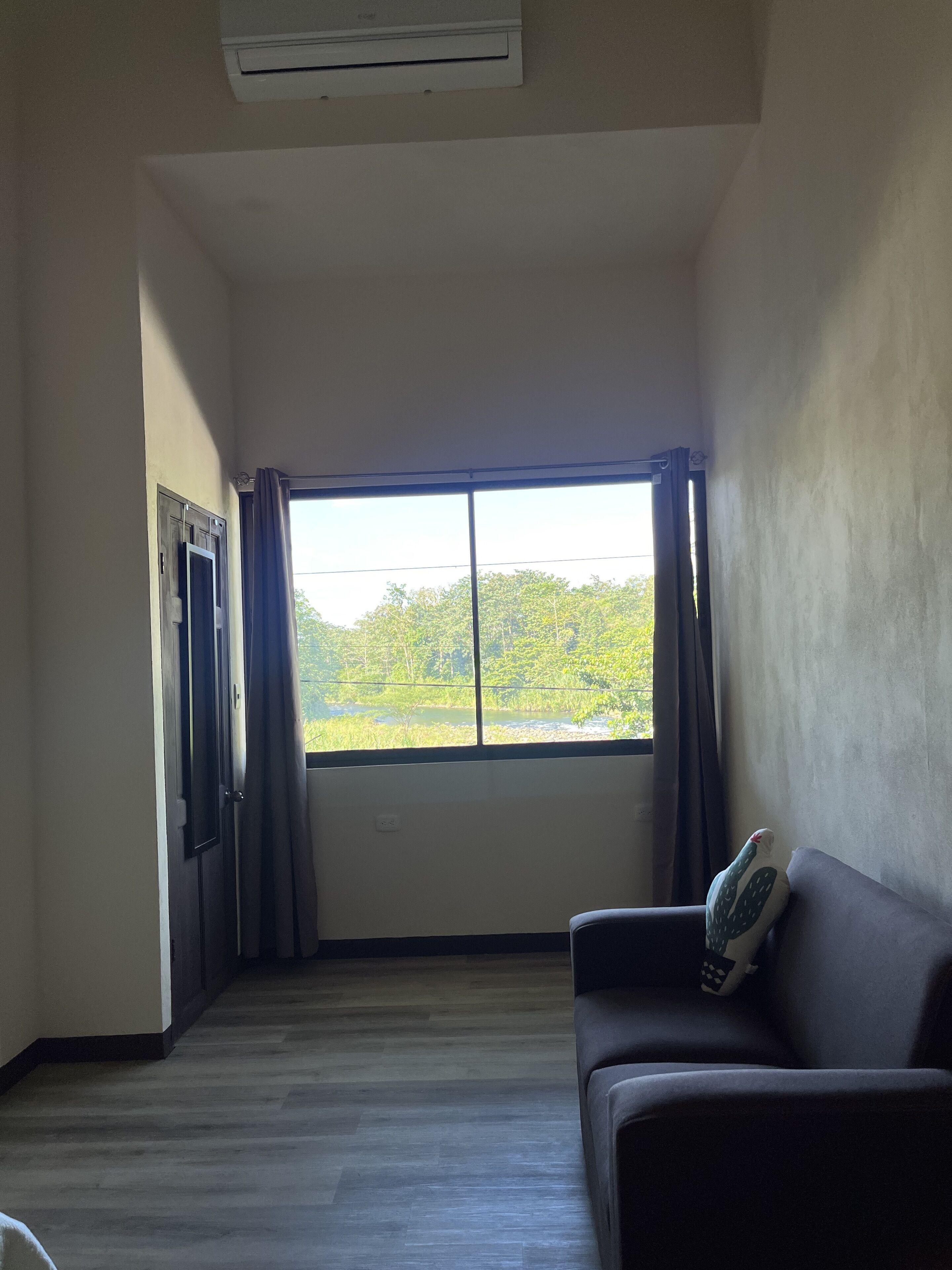 Una habitación con un ventanal amplio, un sofá y una puerta.