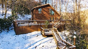 Une cabane en bois dotée d’une terrasse et d’un escalier menant à un balcon.