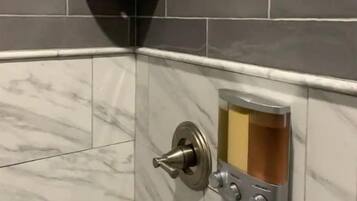 A corner of a bathroom with dark gray tiles and a marble floor.