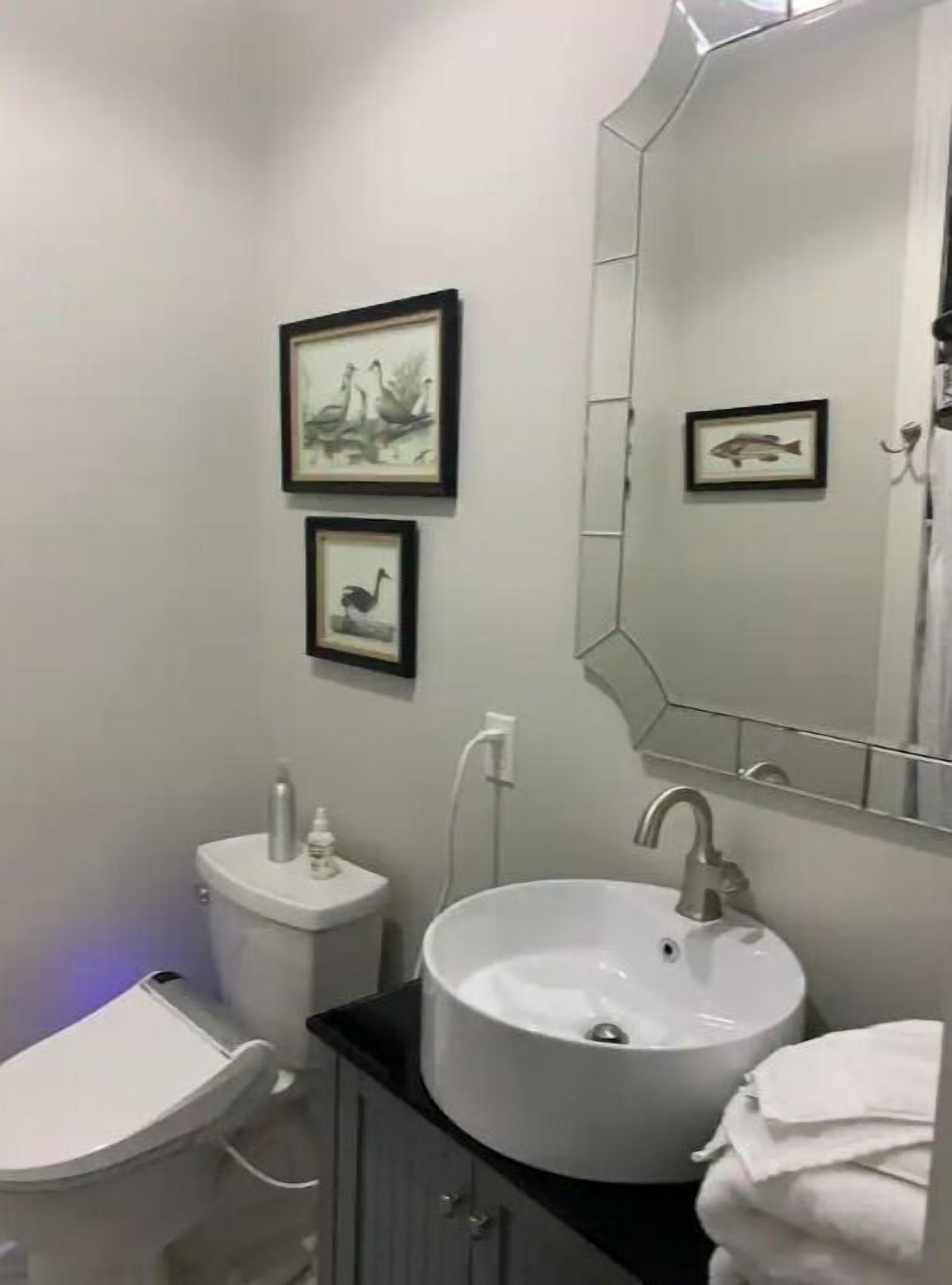 A bathroom with a white sink, a toilet, and two framed pictures on the wall.