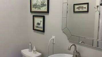 A bathroom with a white sink, a toilet, and two framed pictures on the wall.