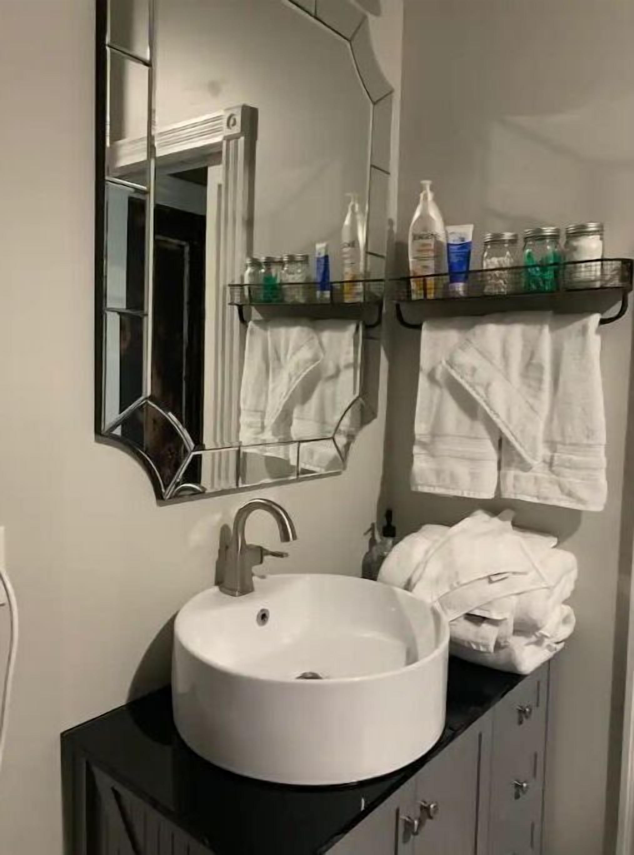 A bathroom with a white sink, a mirror, and a towel rack with towels.