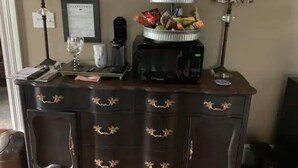 A dark wooden desk with a coffee maker, a tray with snacks, and a framed certificate on the wall. - A Room Off Broadway, a prime downtown hideaway (Bardstown)