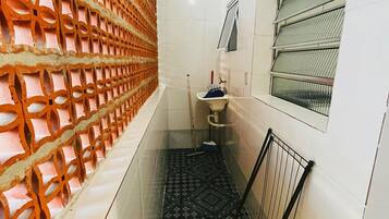 Um corredor estreito com piso estampado, uma pia e uma janela com grades de metal.