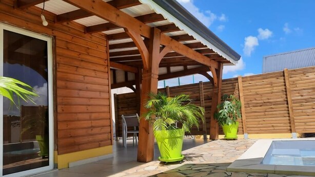 Une cabane en bois dotée d’un patio couvert, d’un sol en pierre et de plantes en pot.