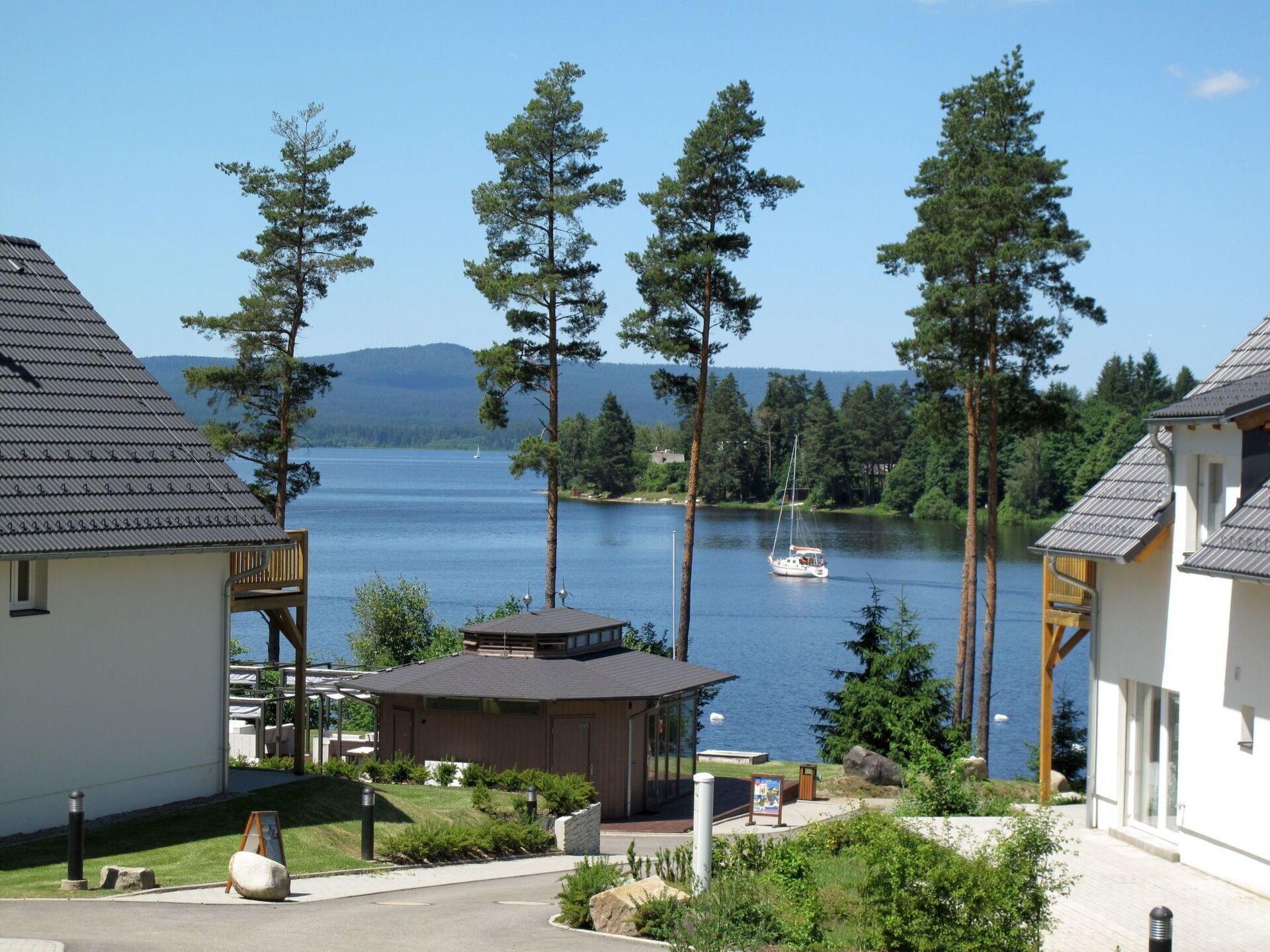 En fastighet vid en sjö med en stuga, en lusthus och en båt som ligger i vattnet.