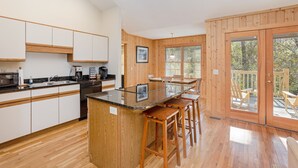 Una cocina moderna con armarios de madera, encimera de granito y una barra con taburetes.