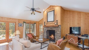 Una sala de estar acogedora con chimenea, paredes de madera y televisor.