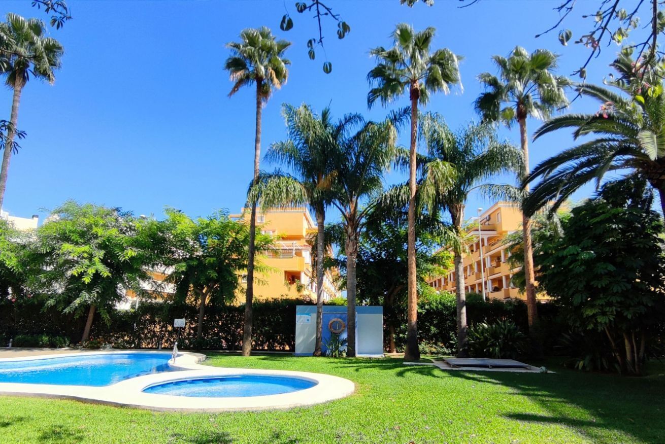 Una piscina rodeada de palmeras y un edificio con balcones.