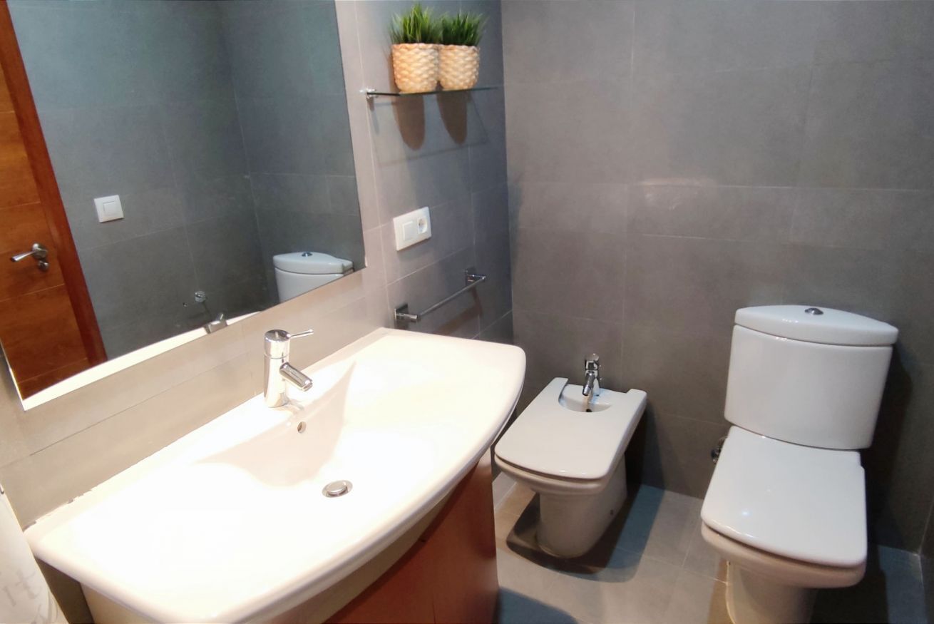 A bathroom with a large sink, a toilet, and a mirror.