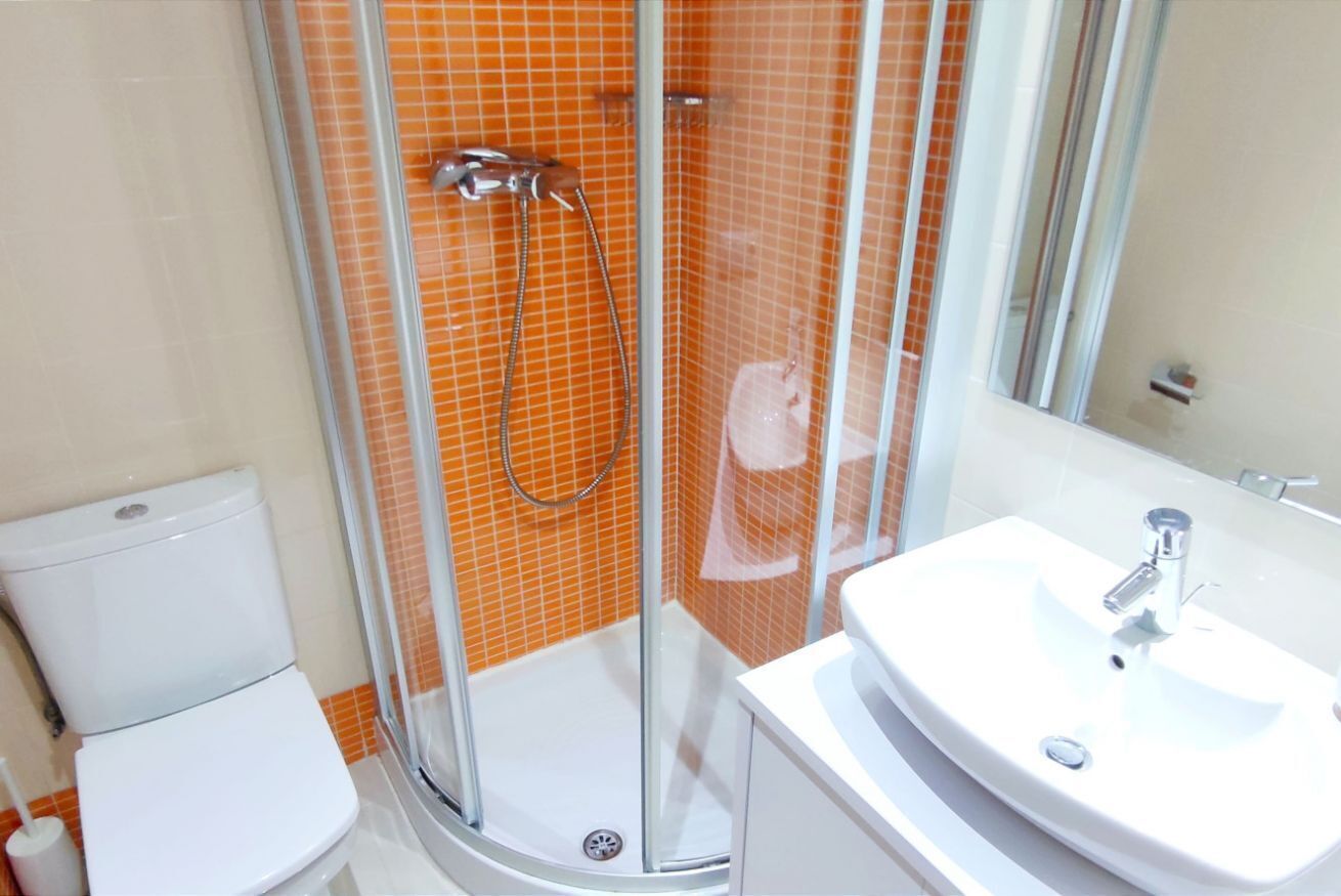 Une salle de bain avec une douche à parois de verre, un lavabo blanc et des toilettes.