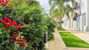 A pathway lined with lush greenery and a row of modern buildings with balconies. - Apartament Victoria Playa by DENIA COSTA (Denia)