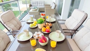 A dining table with chairs, plates, cups, and fruits. - Apartament Victoria Playa by DENIA COSTA (Denia)