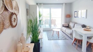 A modern living room with a sofa, dining table, and potted plants. - Apartament Victoria Playa by DENIA COSTA (Denia)