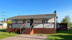 Einbungalow mit Veranda, Satellitenschüssel und kleiner angeschlossener Garage.