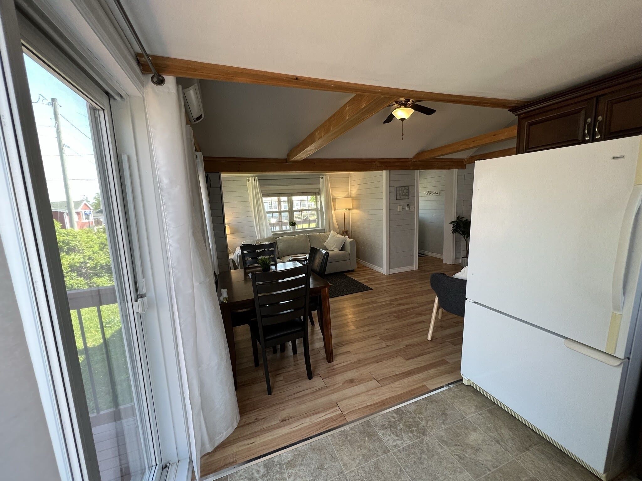 A spacious kitchen with a white refrigerator, wooden flooring, and a ceiling fan.