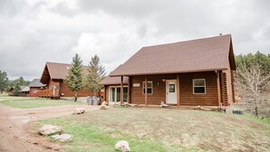 A rustic log cabin with a sloped roof, a front porch, and a visible door. - Welcome to Goldfinch! (Hill City)