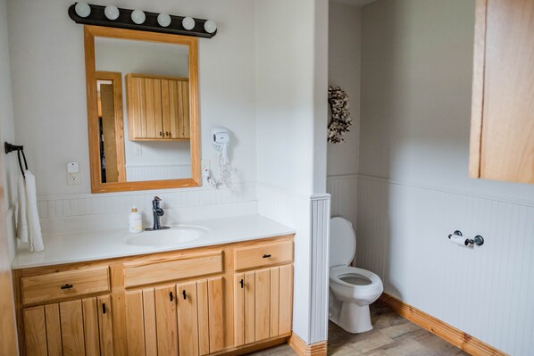 Une salle de bain avec un meuble-lavabo en bois, un lavabo blanc et des toilettes.