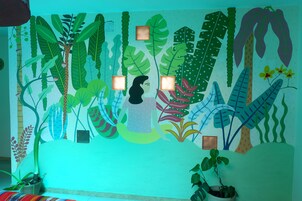 Un mural con diversas plantas tropicales y la silueta de una persona.
