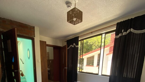 Ein Hotelzimmer mit einem großen Bett, einem Deckenventilator, einem Fenster mit Vorhängen und Blick ins Freie.