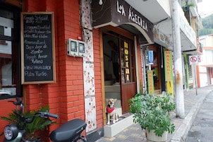 A restaurant with a red brick exterior, a blackboard menu, and a dog sitting outside.