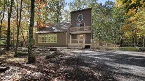 A two-story lodge with a balcony, surrounded by a forested area.