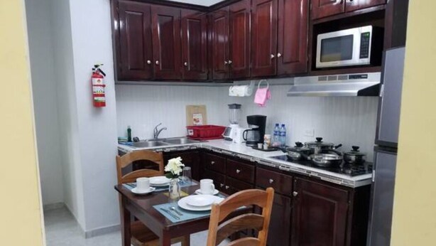 A compact kitchen with dark wooden cabinets, a microwave, and a gas stove. - Royal View Apartment - One bedroom, one bathrooms (Belize City)
