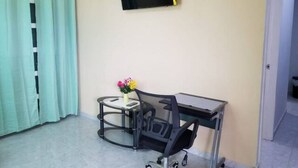 A room with a desk, chair, and a flat-screen TV mounted on the wall. - Royal View Apartment - One bedroom, one bathrooms (Belize City)