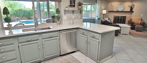 A kitchen with a built-in dishwasher, a dining area with a table and chairs, and a fireplace.