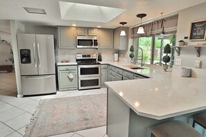 A modern kitchen with a central island, built-in appliances, and a large window providing natural light. - Sabino Vista Charming Quiet Home with Pool (Tucson)