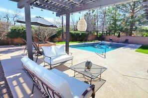 A covered outdoor area with a pool, lounge chairs, and a table. - Sabino Vista Charming Quiet Home with Pool (Tucson)
