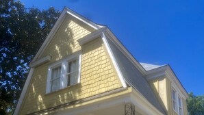 A two-story house with a brick front porch and a small set of stairs leading to the entrance. - Adorable 1899 historic “The Butter Bean Lady” storybook home (Columbus)