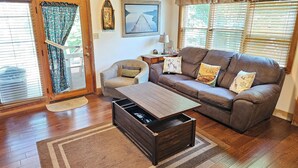A cozy living room with a brown leather sofa, a wooden coffee table, and a patterned rug.