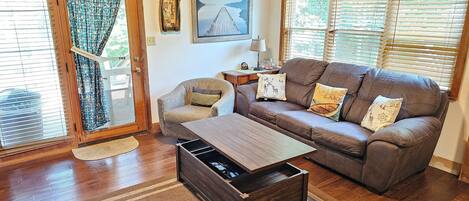 A cozy living room with a brown leather sofa, a wooden coffee table, and a patterned rug.