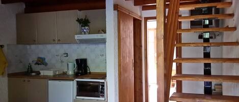 A compact kitchen with wooden beams, a built-in oven, and a small refrigerator.