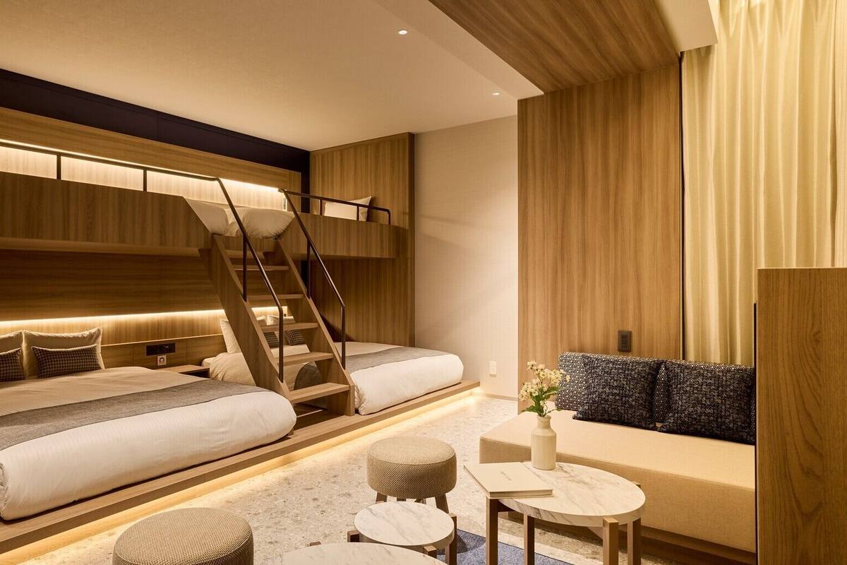 Une chambre d’hôtel moderne équipée d’un lit superposé, d’un canapé, d’une petite table et d’un escalier.