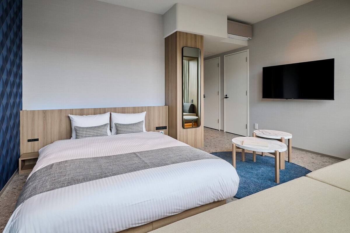 Une chambre d’hôtel avec un lit, une télévision, une petite table et un miroir.
