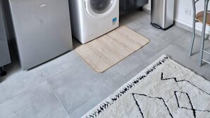 Une cuisine compacte équipée d’un lave-linge intégré, d’un évier et d’un four à micro-ondes.