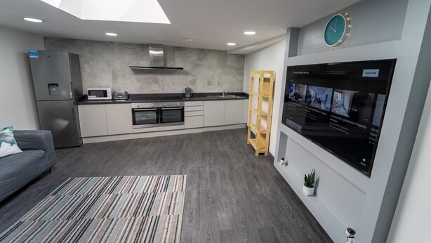 Una cocina moderna con horno integrado, un refrigerador y una escalera de madera.