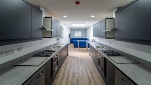 A modern kitchen with two gas stoves, a central island, and a blue sofa in the background. - Lovely homely studio available (Birmingham)