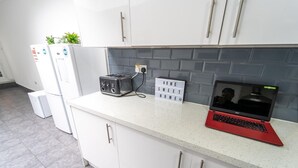 A kitchen with white cabinets, a countertop, a toaster, a laptop, and a sign that reads "HOME SWEET HOME." - Large studio 10 minute train journey to the city! (Birmingham)