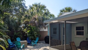 A patio area with outdoor seating, a covered table, and a glass enclosure. - "Happy Ours" Gulfport - charming home, walk to beach and town (Gulfport)
