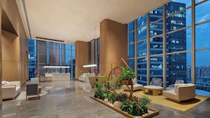 A spacious lobby with a reception desk, seating areas, and large windows offering city views. - Wyndham Guangzhou Baiyun Mountain (Guangzhou)