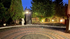 A paved courtyard with a stone statue, a wooden fence, and a stone lantern. - Holiday Home 'Balke' with Mountain View, Garden, Terrace & Wi-Fi (Hatzfeld)