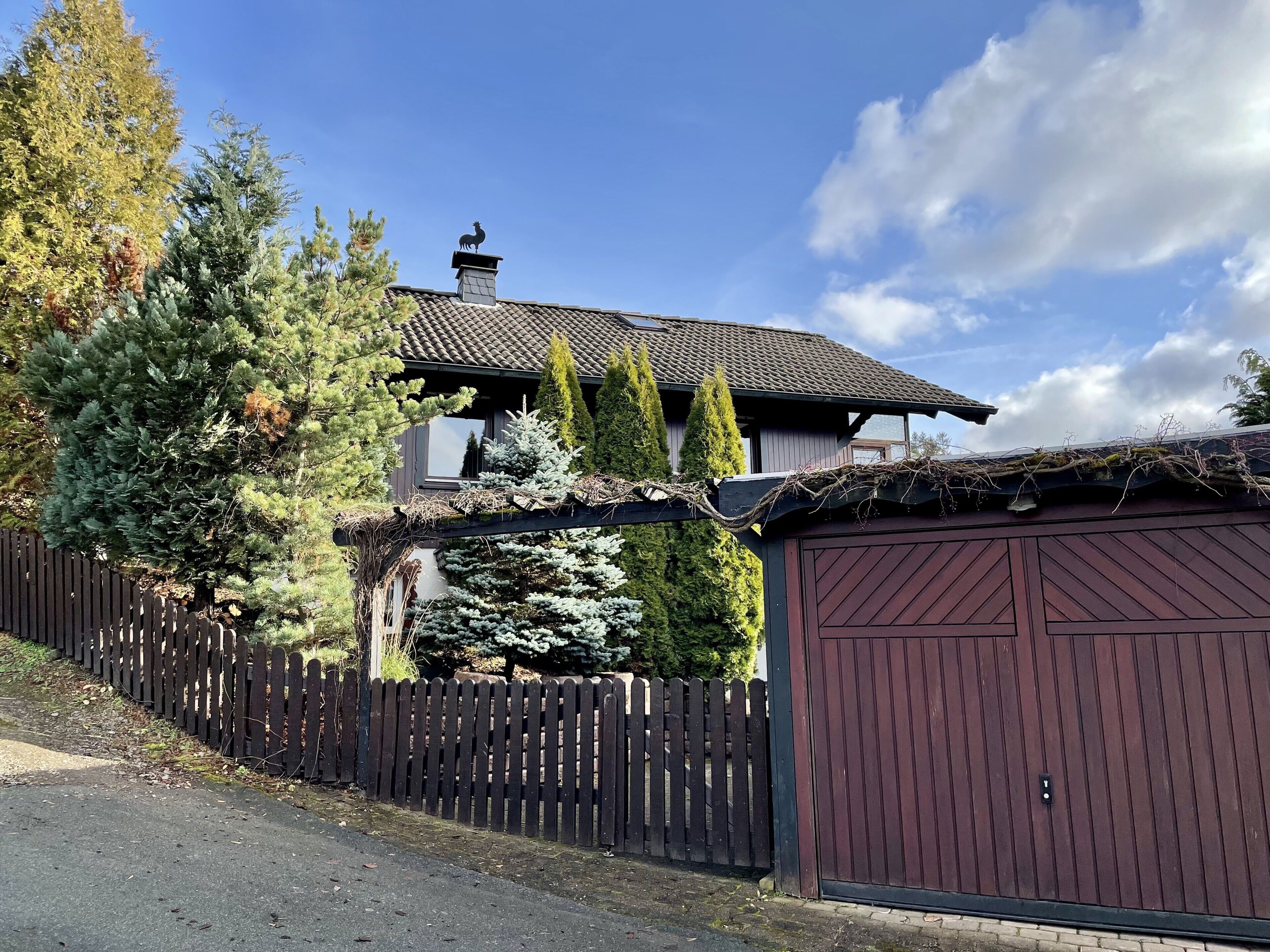 A house with a chimney, a wooden fence, and a garage.