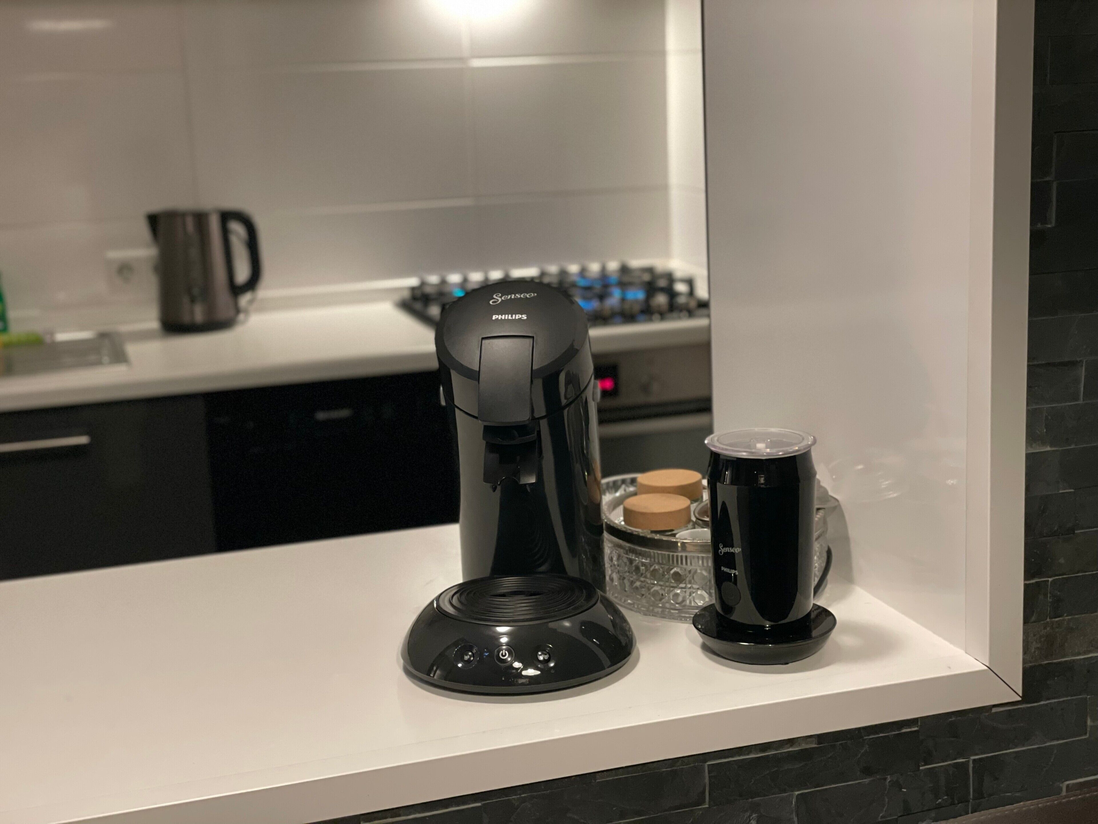 Una cocina moderna con una cafetera, un recipiente de vidrio y una tetera sobre la encimera.