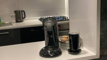 Una cocina moderna con una cafetera, un recipiente de vidrio y una tetera sobre la encimera.