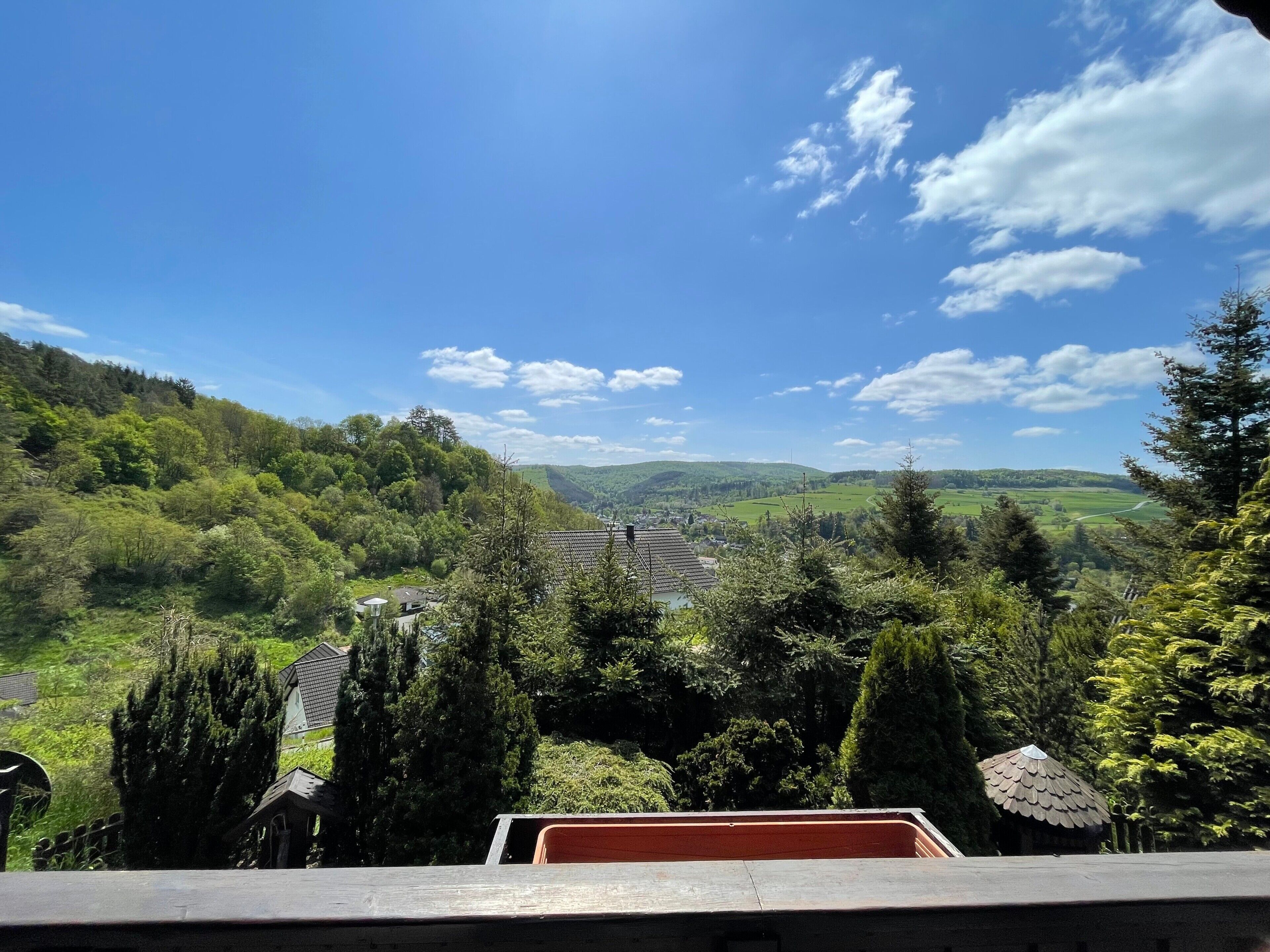 Blick auf ein Tal mit einem Haus und Bäumen.