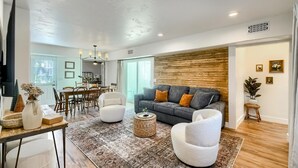 A modern living room with a grey sofa, white armchairs, and a patterned rug. - Wine Trail Retreat w/ Fire Pit, Cold Plunge, Grill, Walk to Downtown JC! (Johnson City)