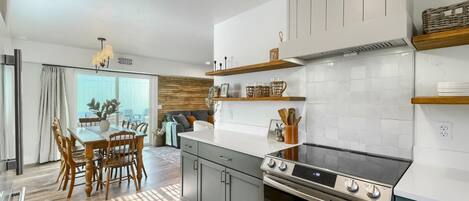 Una cocina moderna con estufa a gas, armarios de madera y un comedor con mesa y sillas.